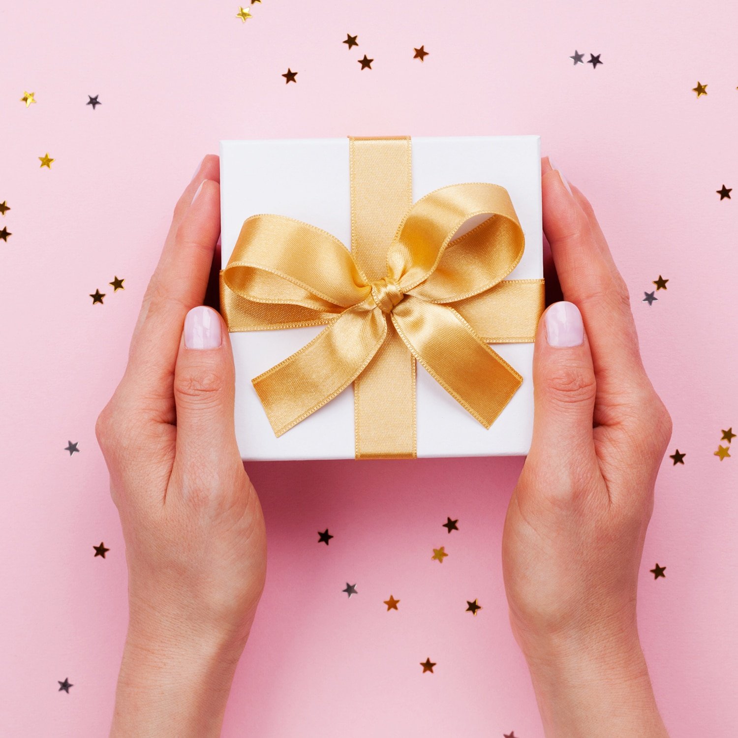 Womans hands holding gift or present box decorated confetti on p