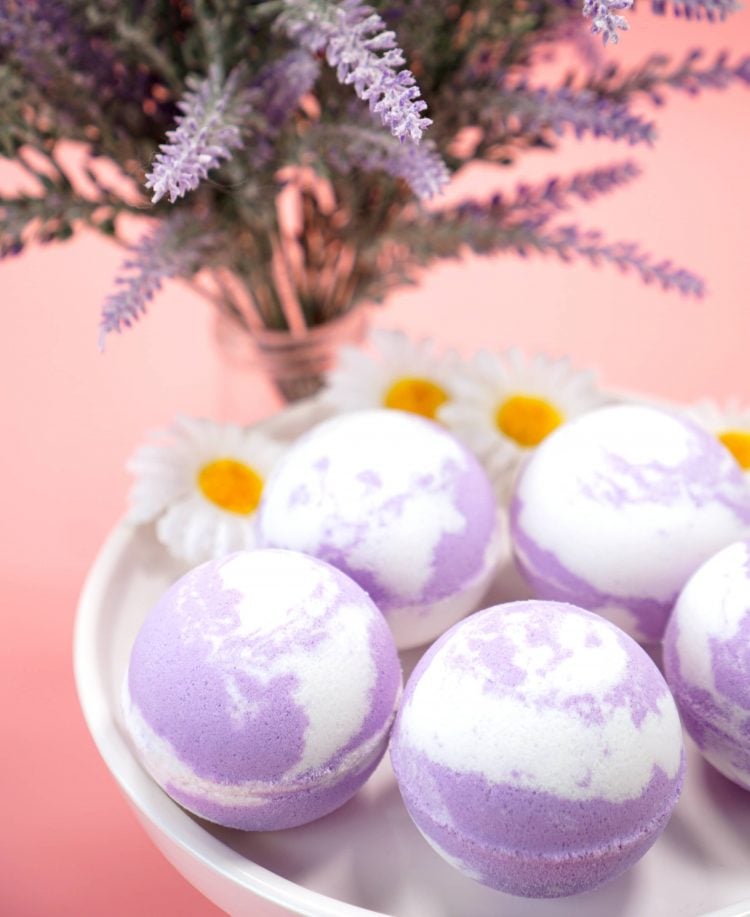 lavender and white bath bombs on a dish with lavender flowers in background