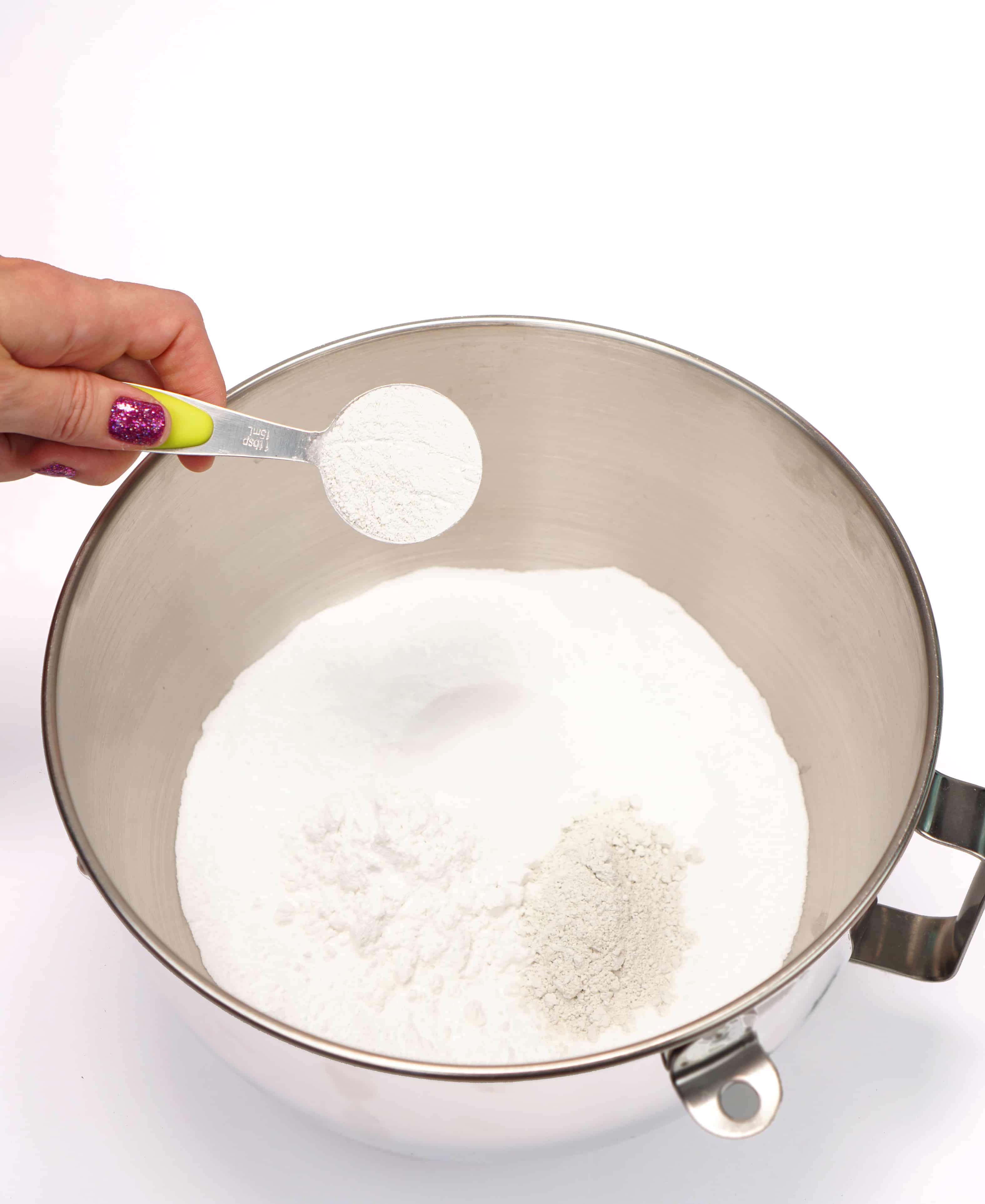Adding dry ingredients to a mixing bowl to make bath bombs
