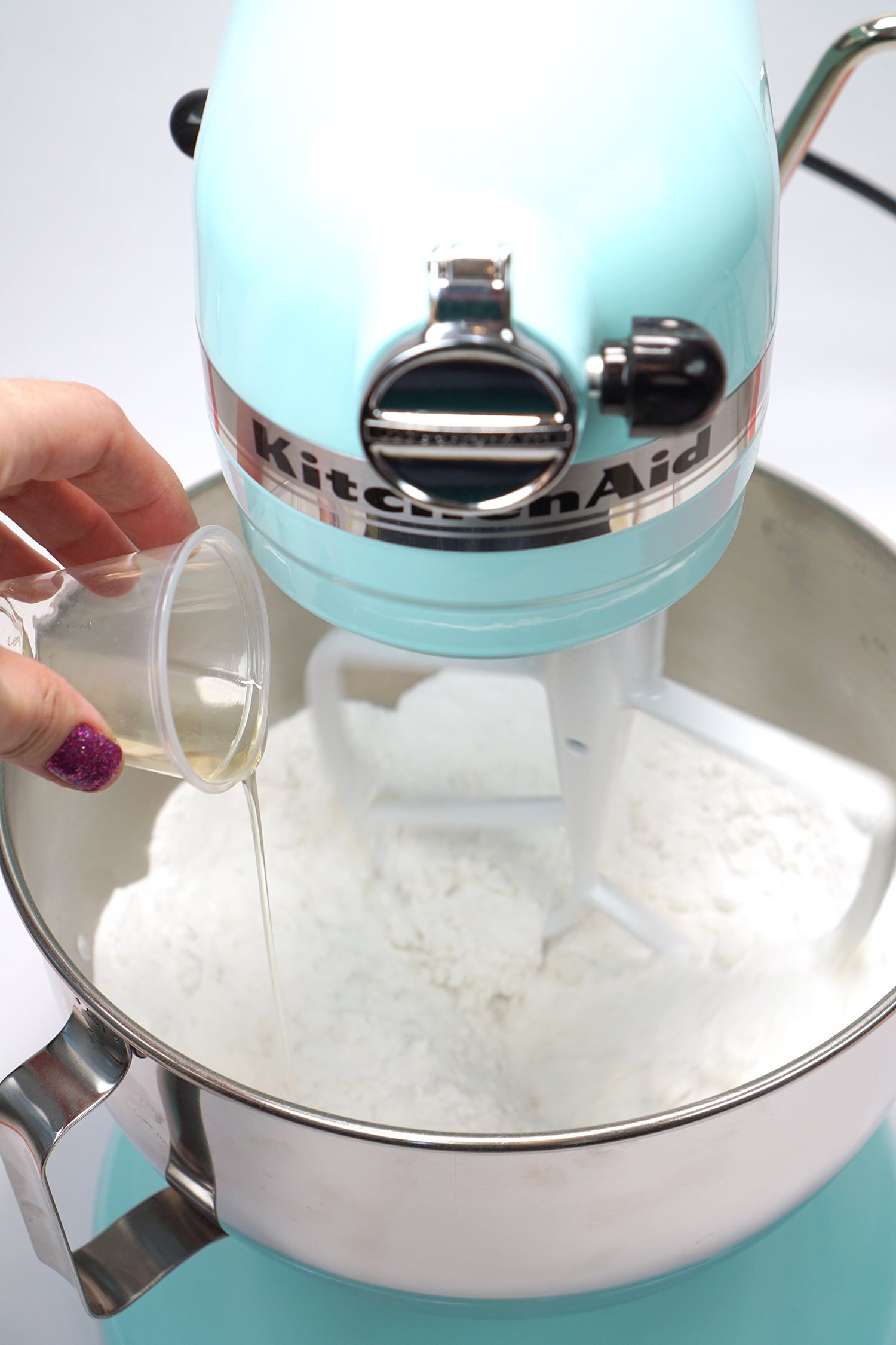 Pouring wet bath bomb ingredients into dry bath bomb recipe mixture