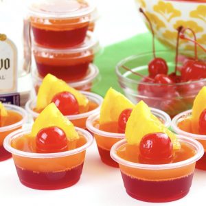 jello shots garnished with maraschino cherries and pineapple slices