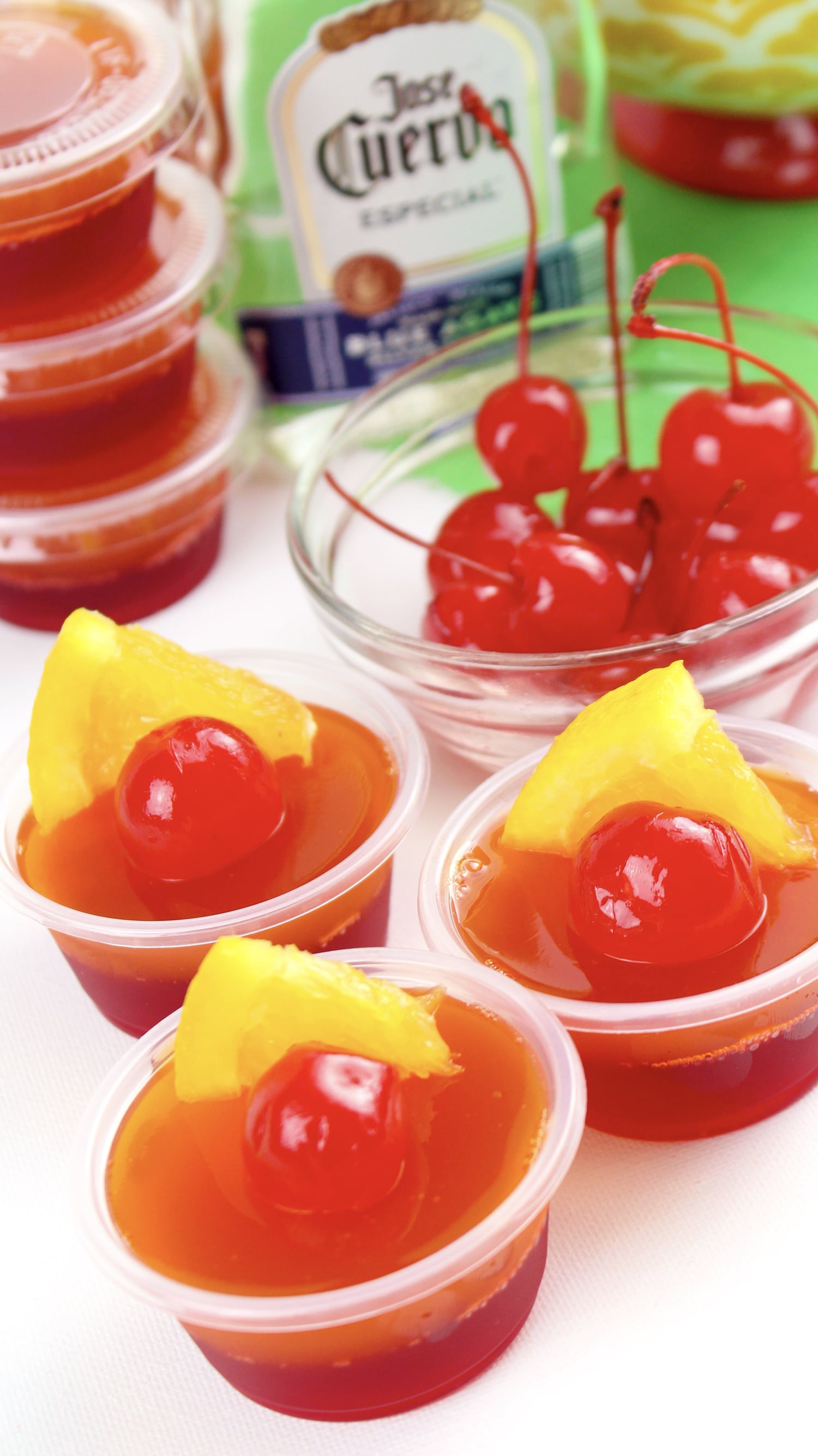 jello shots garnished with maraschino cherries and pineapple slices