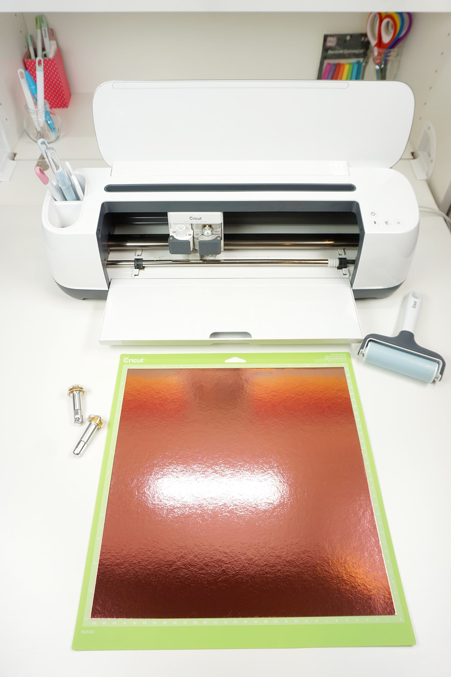 cricut foil adhered to cutting mat in front of cricut machine with tools