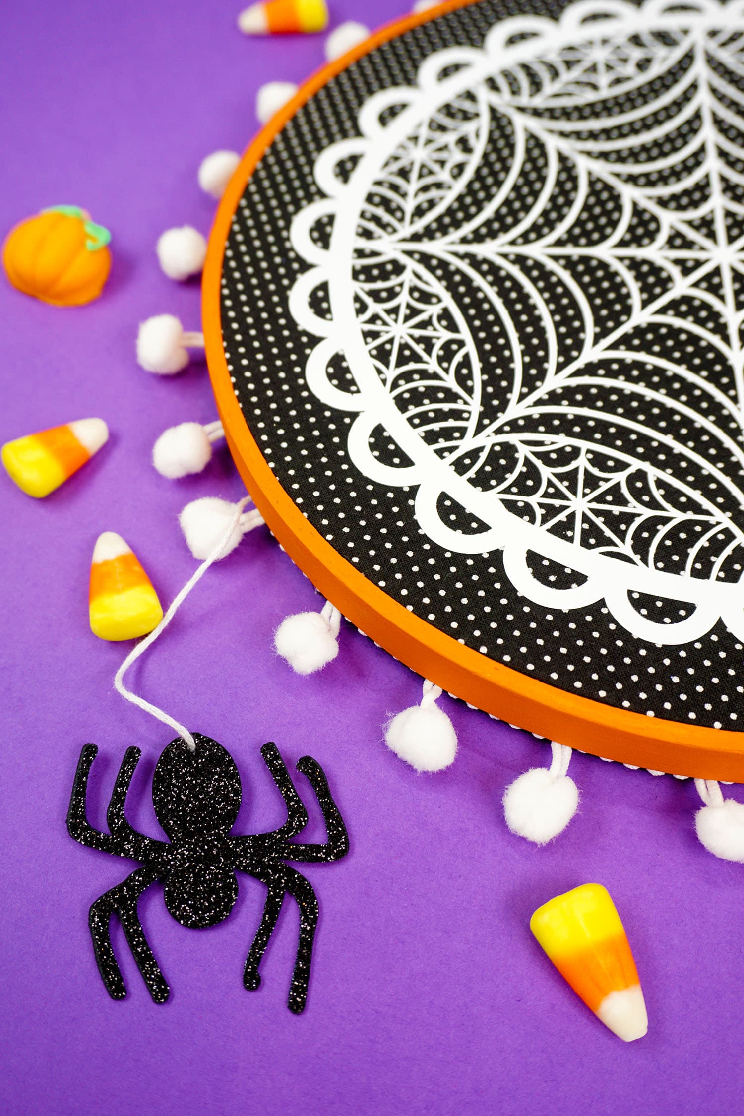 spider dangling from spider web embroidery hoop project with candy corns