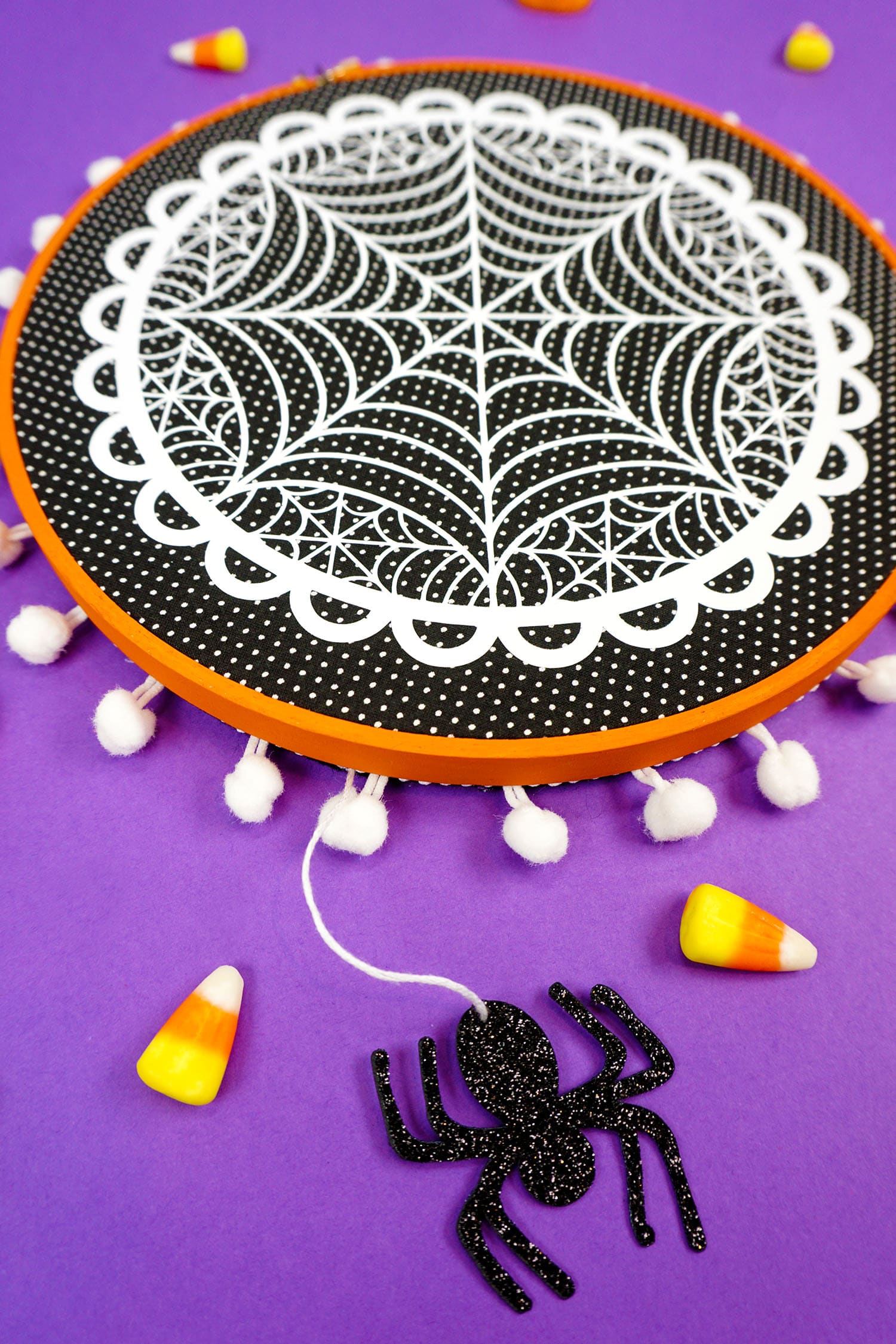 spider dangling from spider web embroidery hoop project