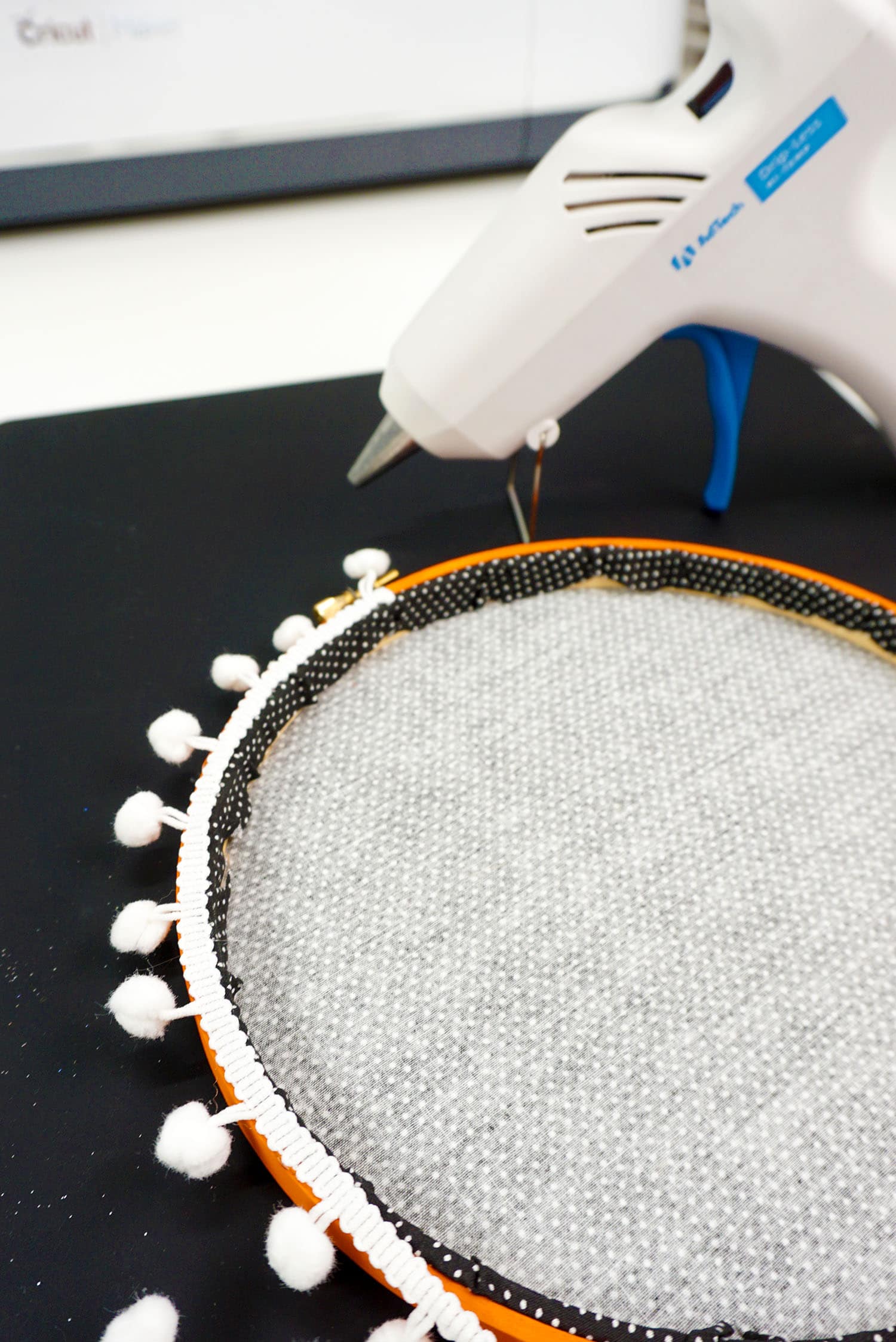 hot glueing white pom poms to outer edge of hoop