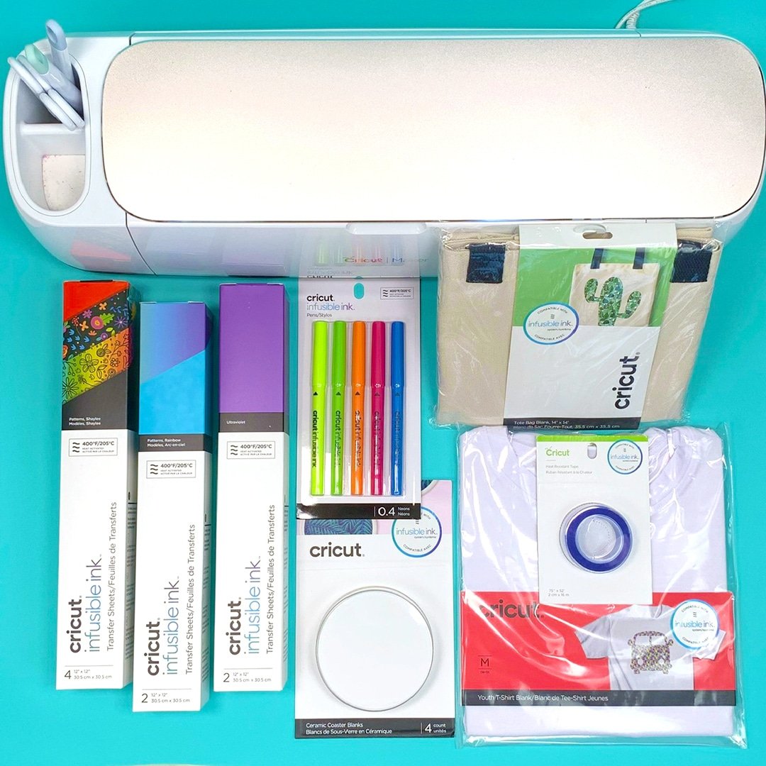 A Cricut Maker With Cricut Infusible Ink, Infusible Ink Pens, Infusible Ceramic Coasters, an Infusible Hand Bag,an Infusible Shirt, and Cricut Heat Resistant Tape.