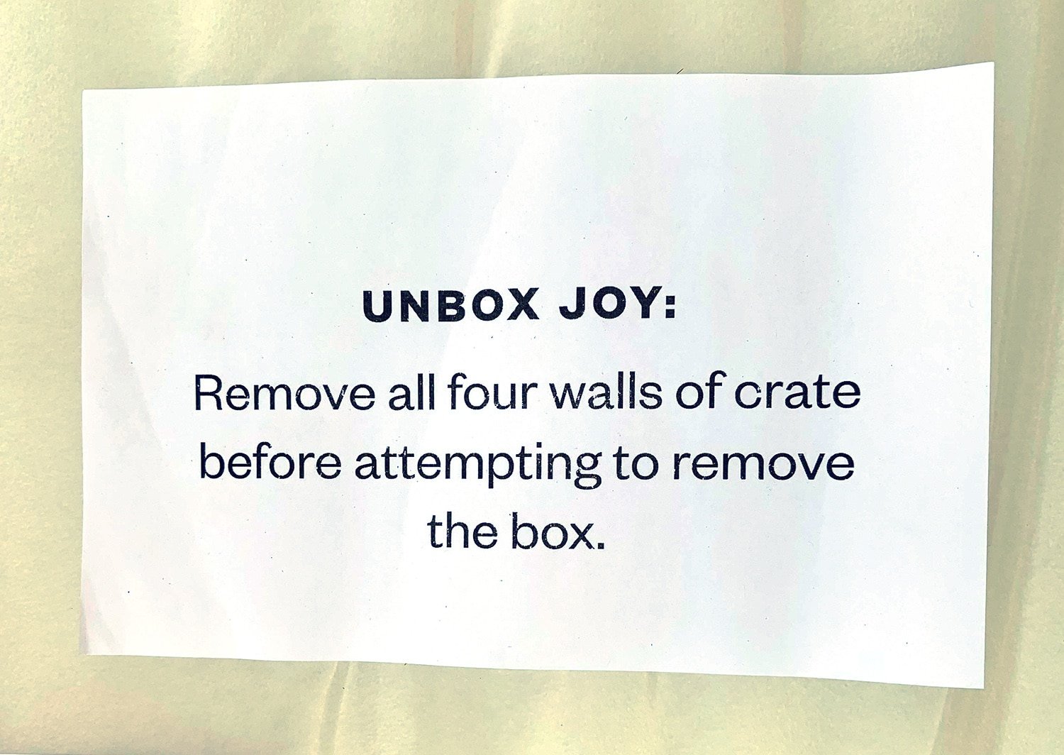 piece of paper reads unbox joy: remove all four walls of crate before attempting to remove the box