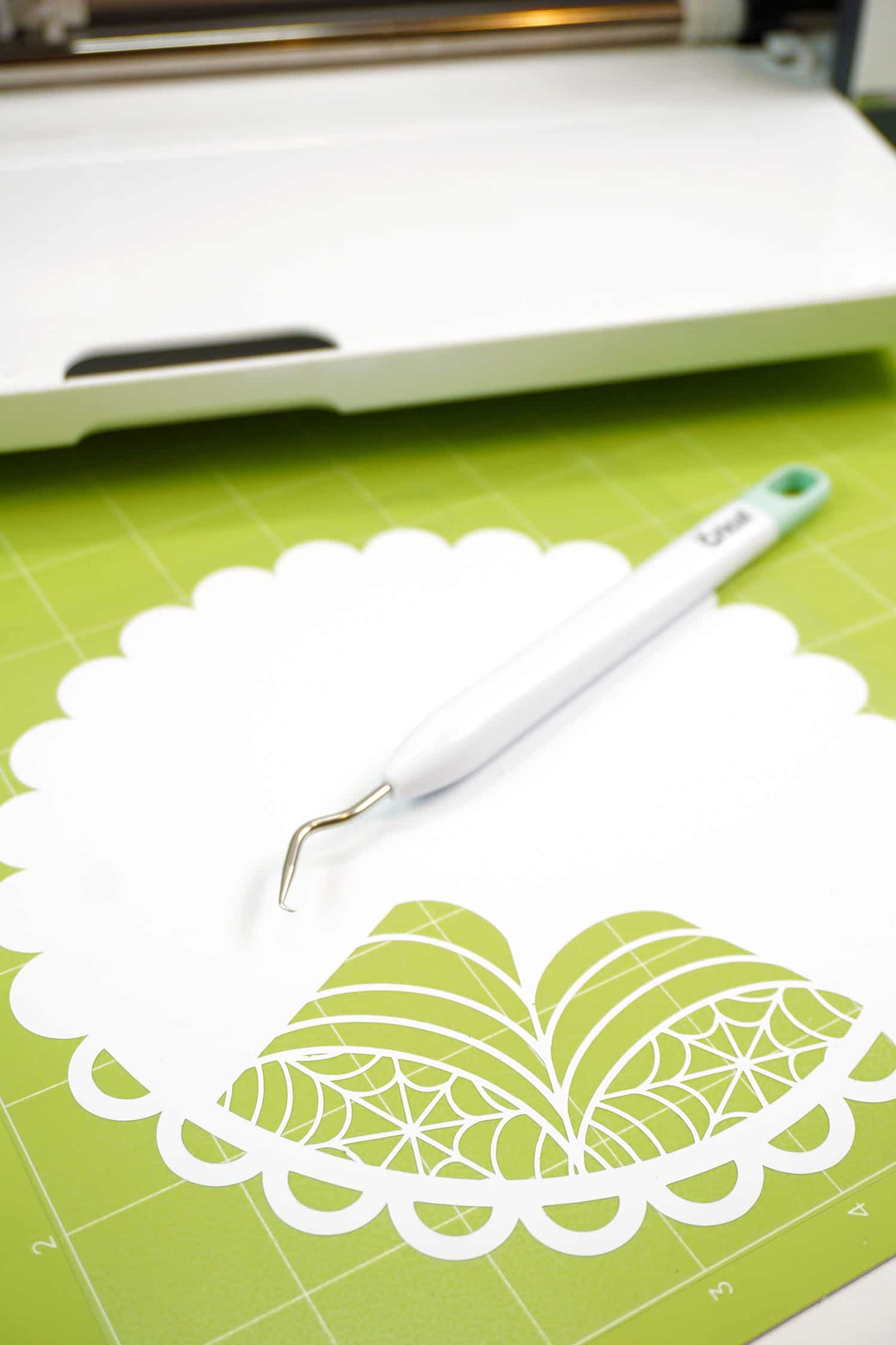 weeding tool and spider web design on cricut cutting mat