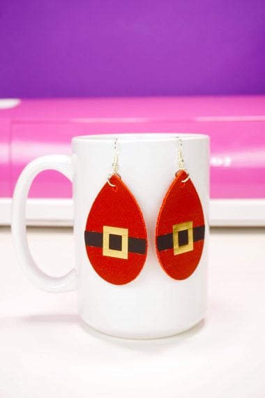 cricut cut santa belt earrings hanging on mug