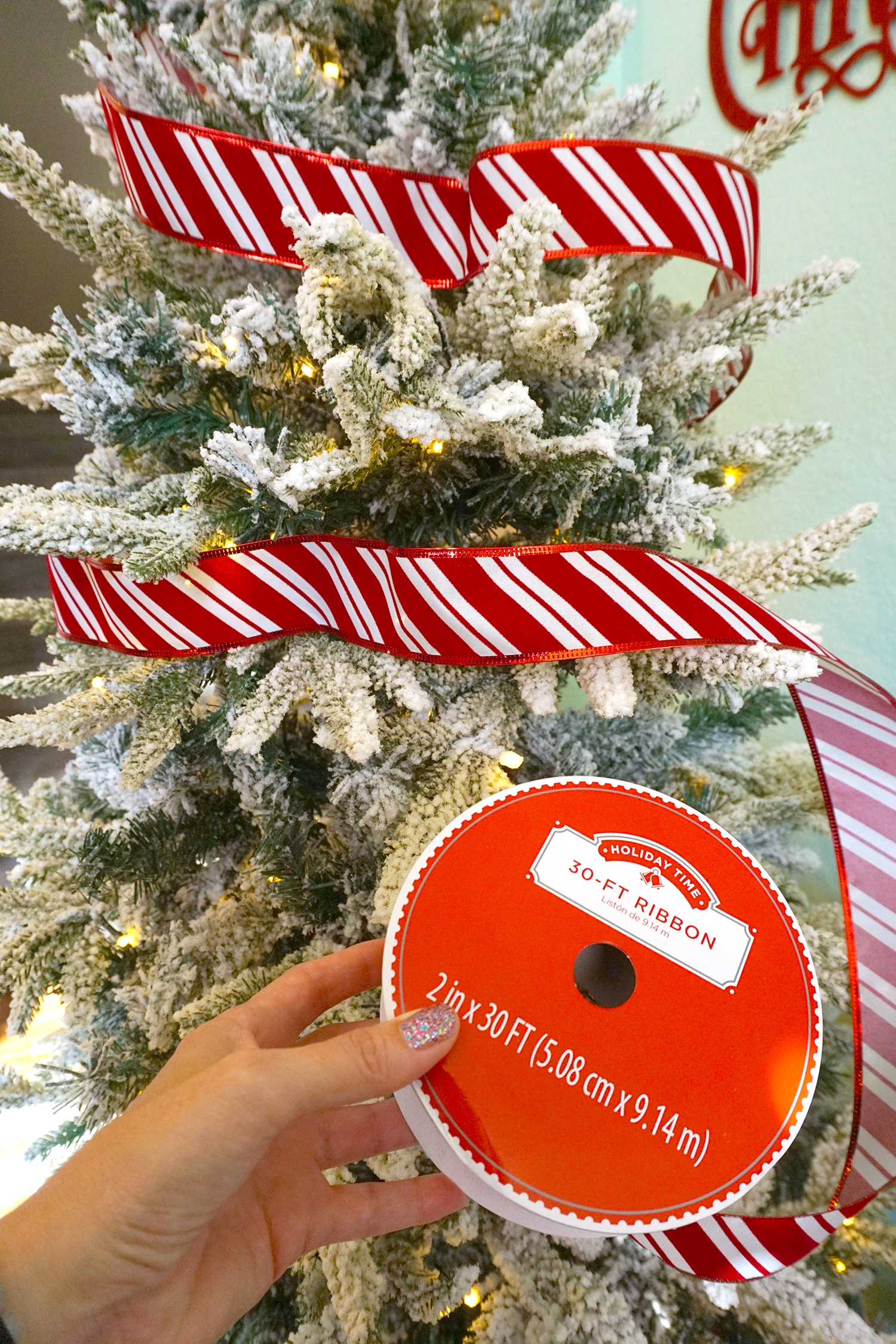 candy cane striped ribbon being place on christmas tree