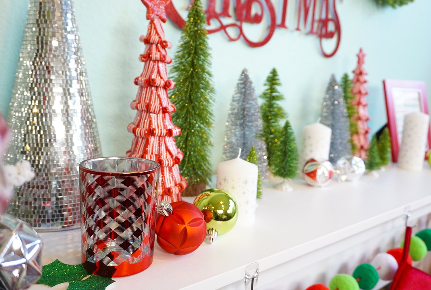 top of mantel decorated with trees and candles and christmas baubles 