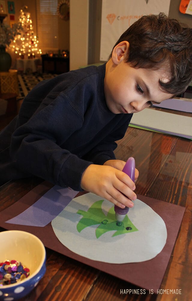 child decorating a paper christmas tree