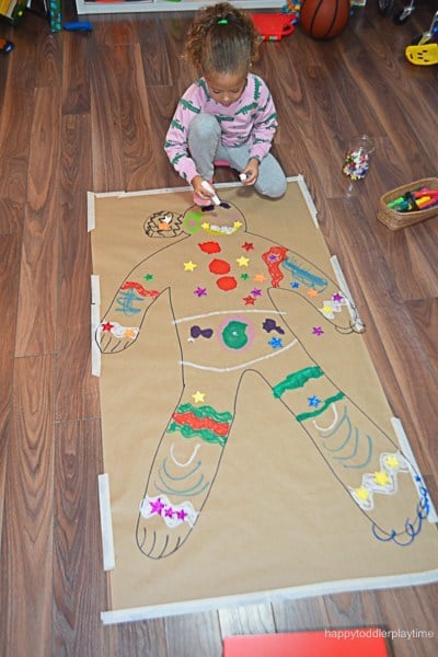 gingerbread girl drawn on cardboard being decorated by kid