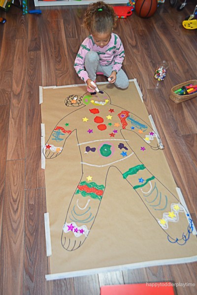 gingerbread girl drawn on cardboard being decorated by kid