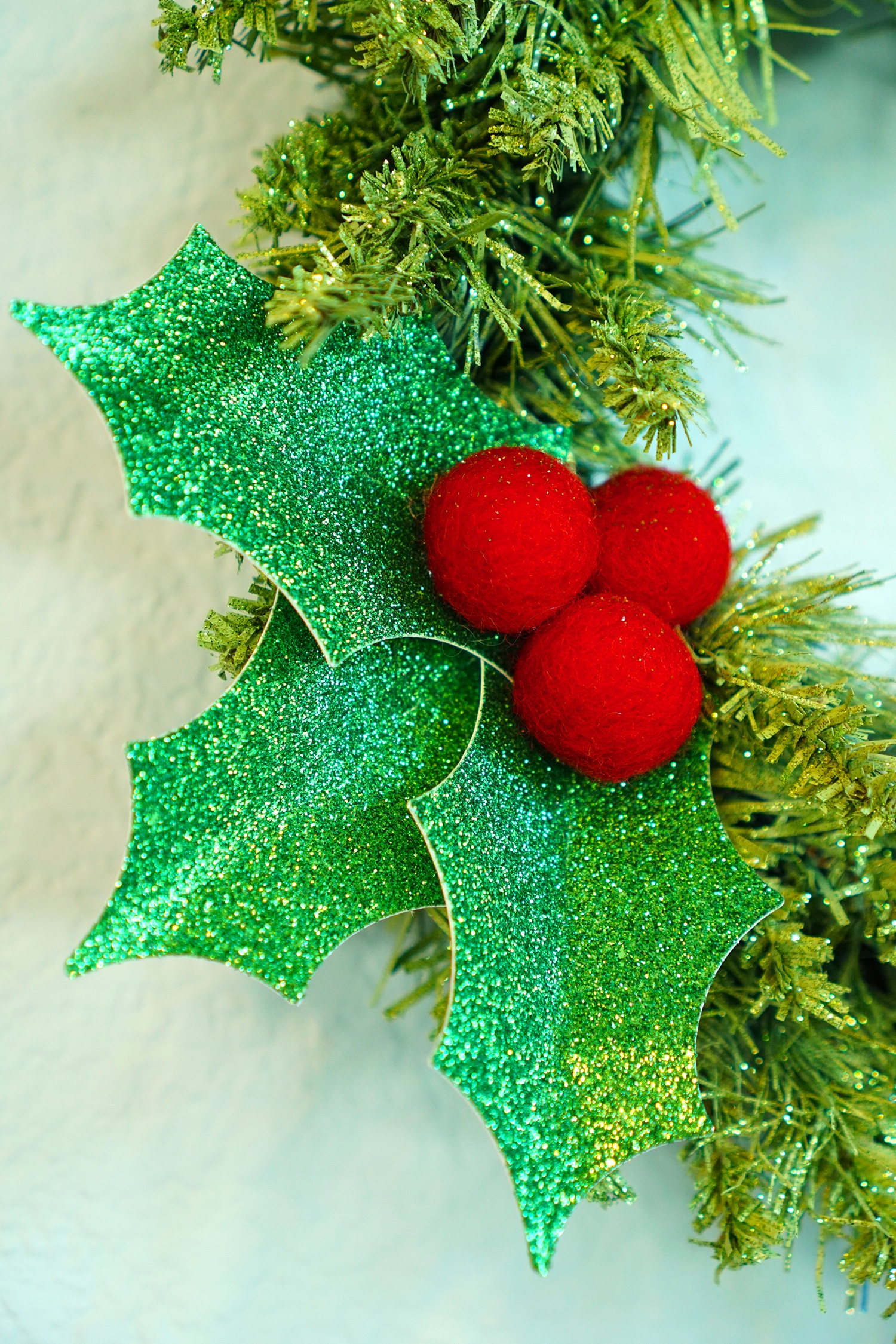 close up of holly berry leaves made from cricut and red pom pom balls