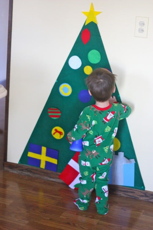 kid decorating paper christmas tree on wall