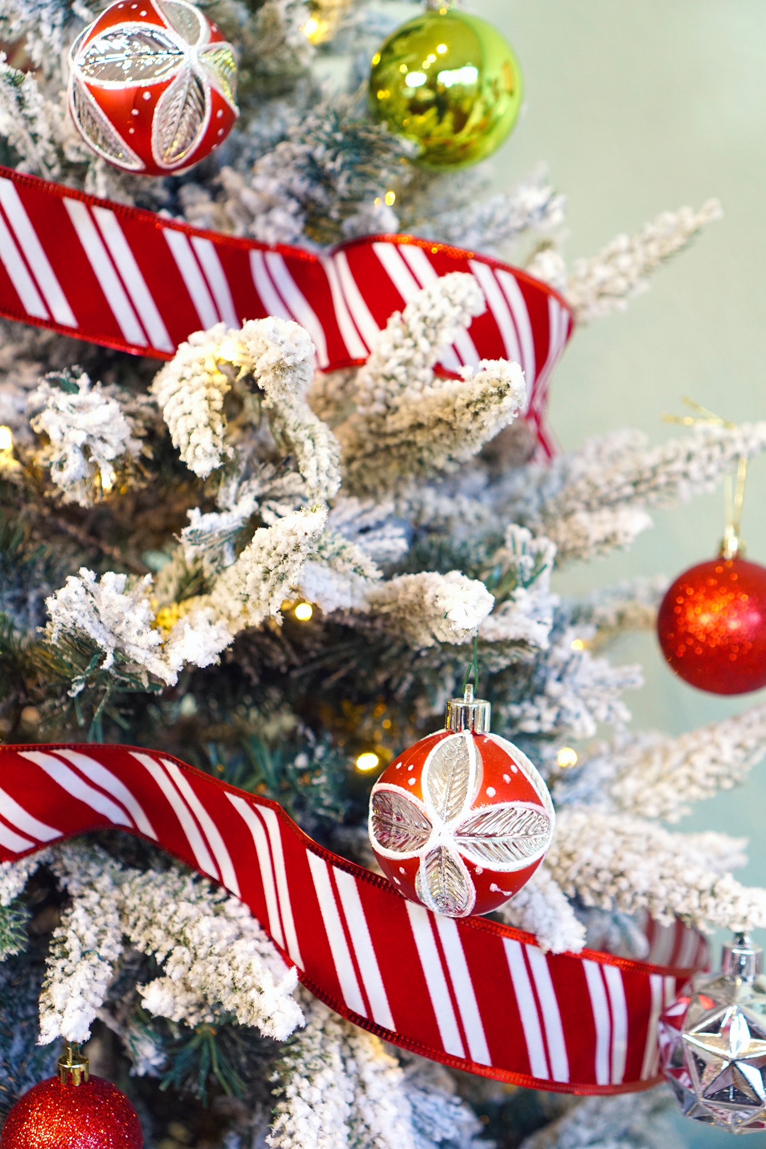 red and lime ornaments on flocked christmas tree