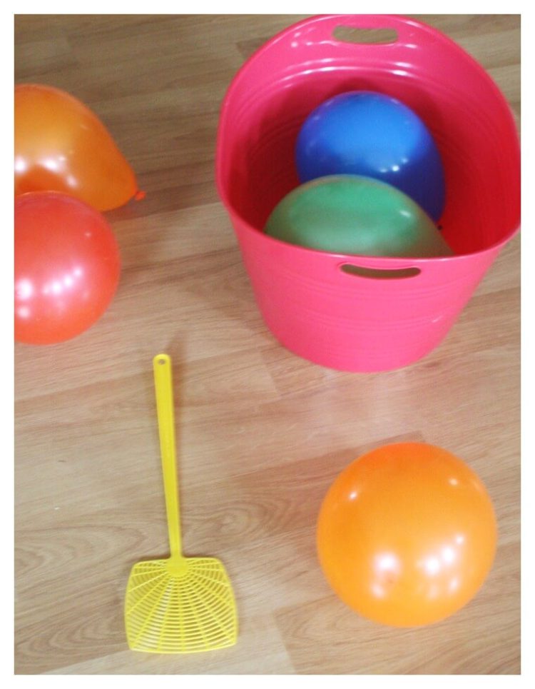 Balloon tennis game pieces fly swatter and balloons blown up in basket