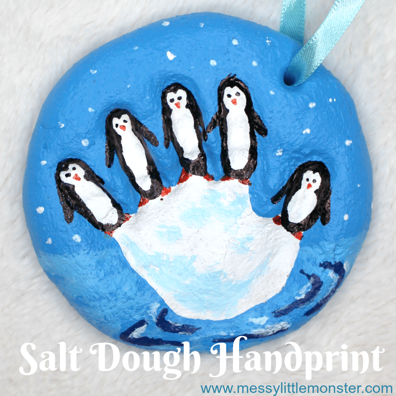 salt dough ornament featuring kids hand print with fingers turned into penguins on top of a block of ice