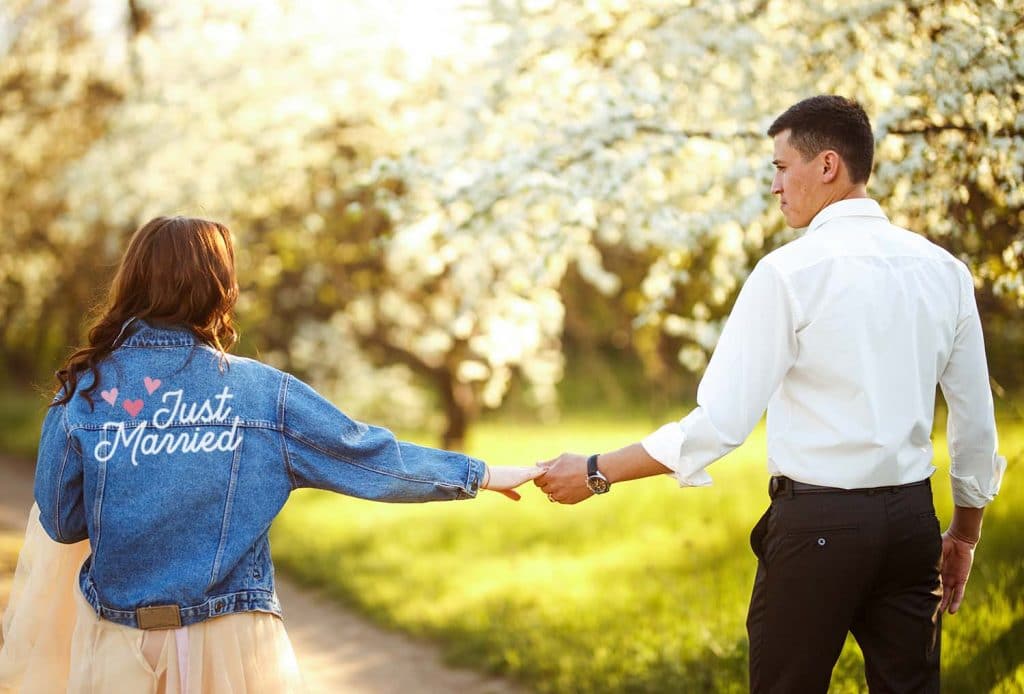 couple holding hand wearing denim just married jacket