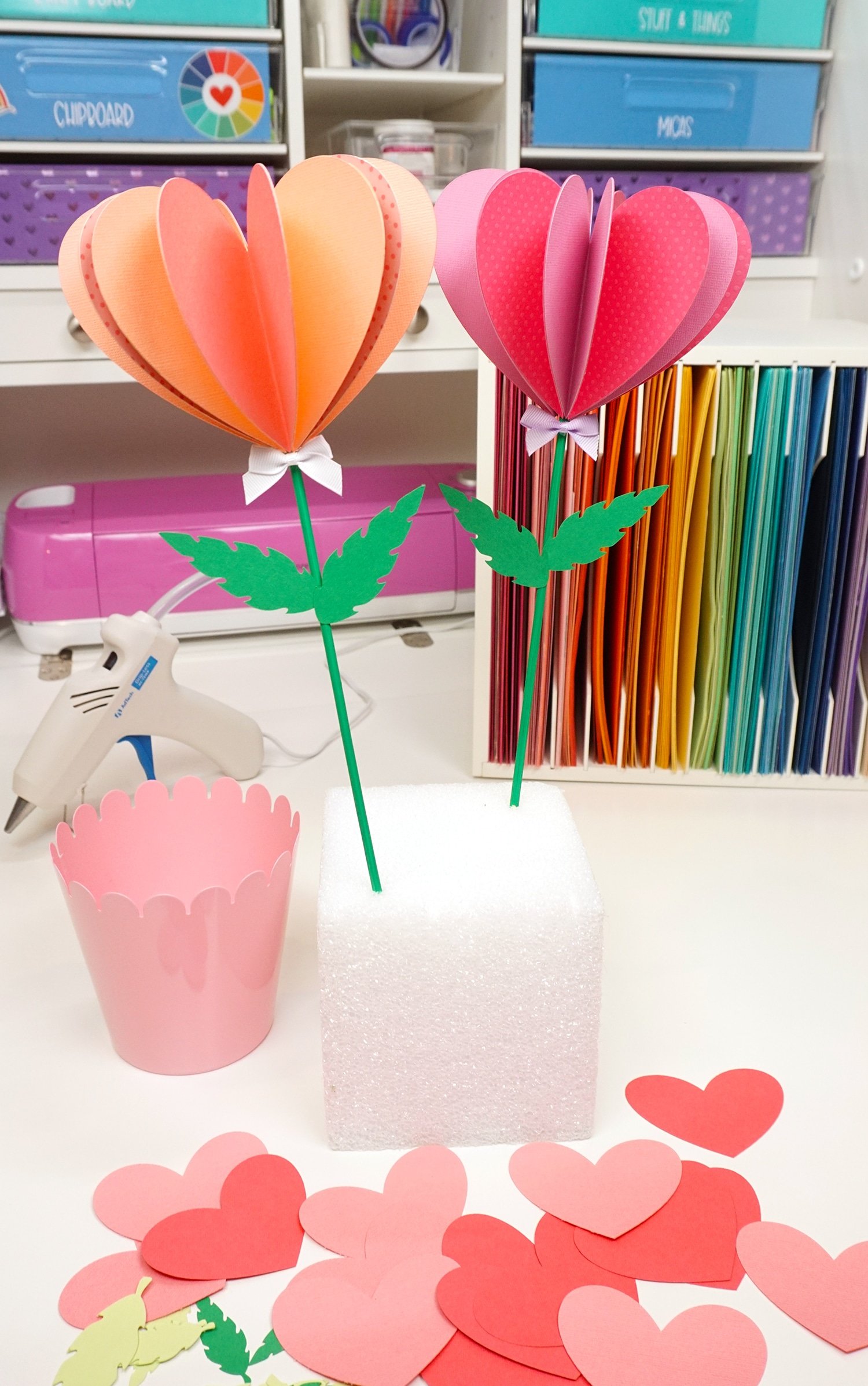 paper heart flowers stuck into foam block with pot next to it and paper organizer and glue gun