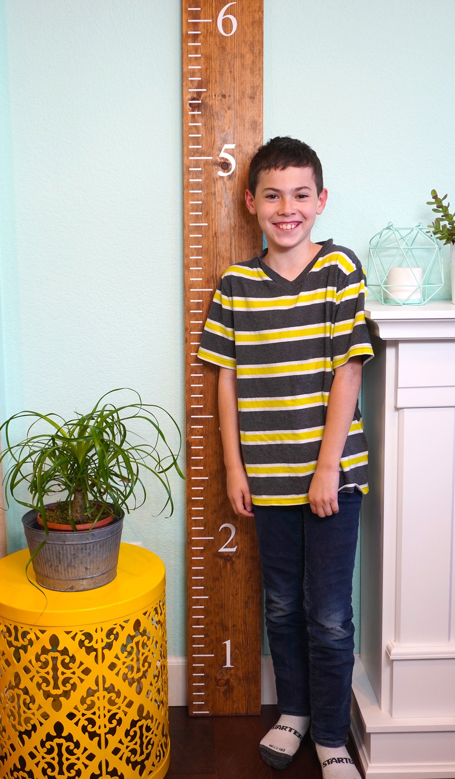 child measured next to ruler growth chart in living space