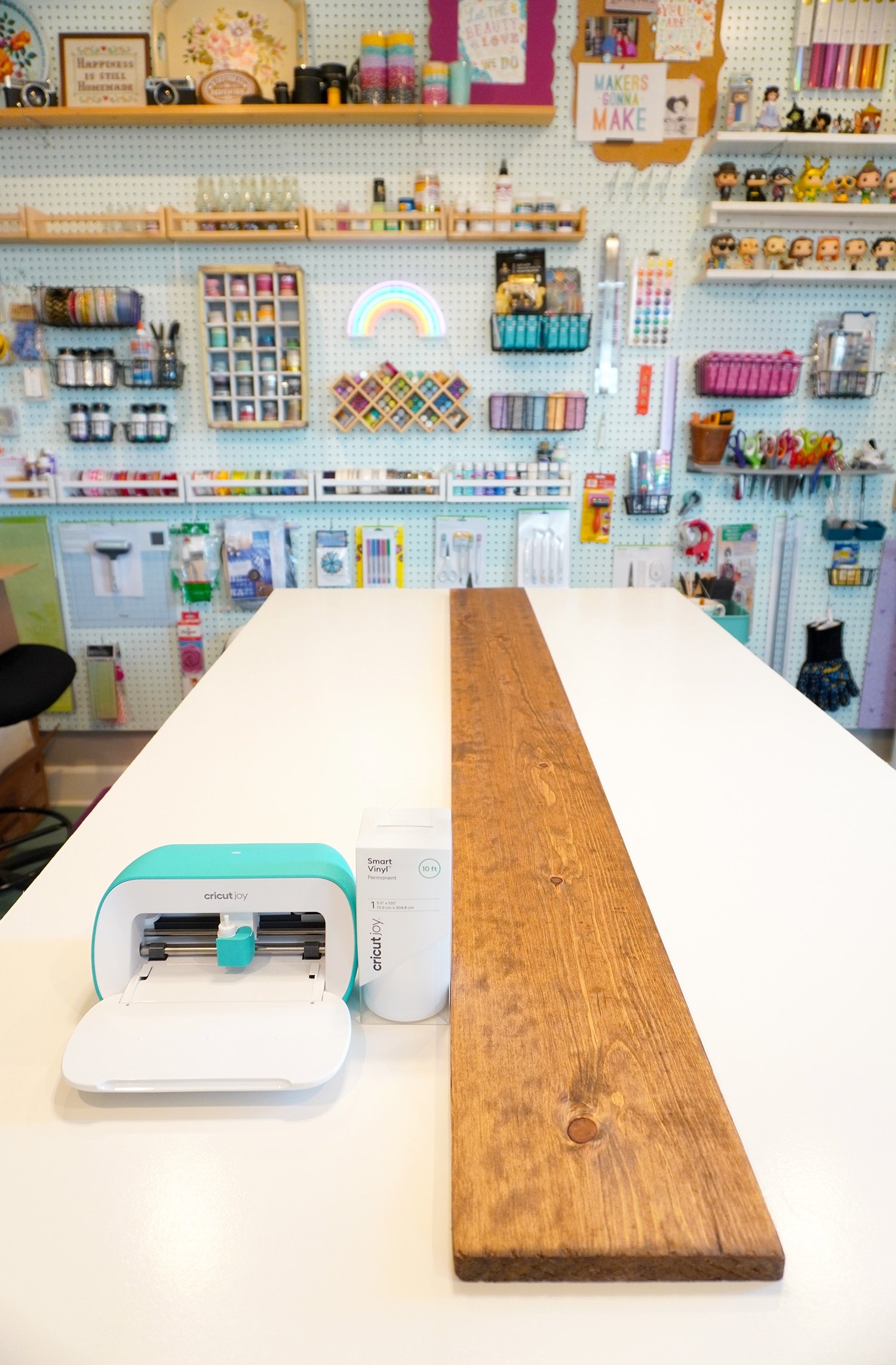 craft table with cricut machine and long wooden board inside of craft room