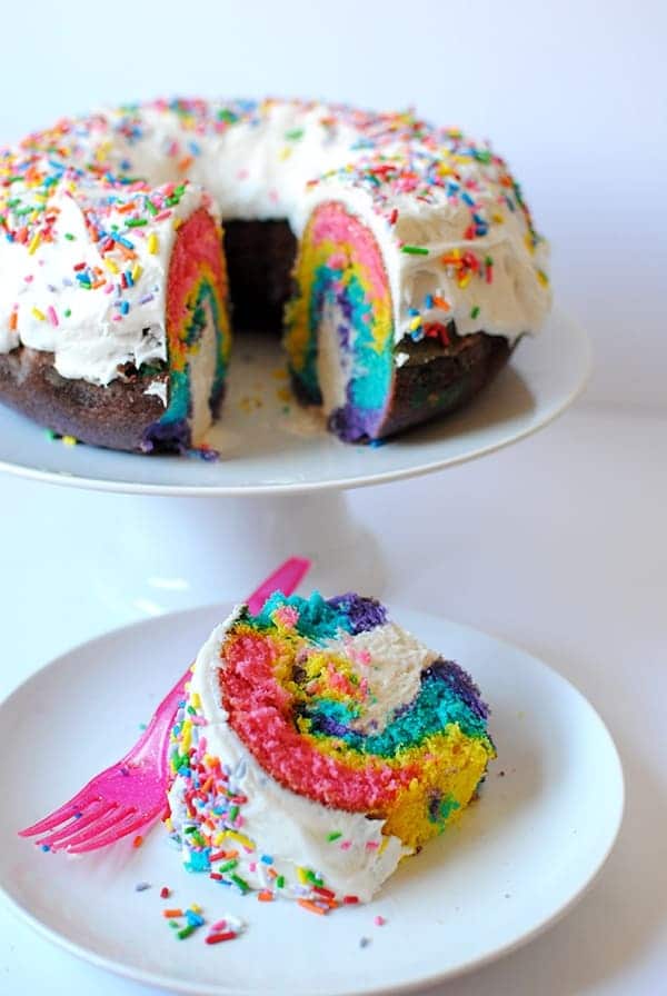 rainbow unicorn iced cake with slice cut on plate