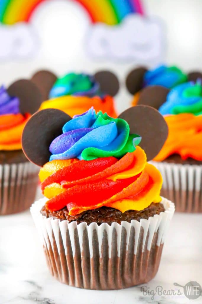 rainbow iced cupcakes with chocolate ears that resemble mickey mouse heads