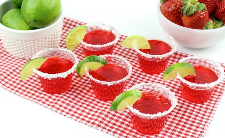 strawberry margarita jello shots on table with limes