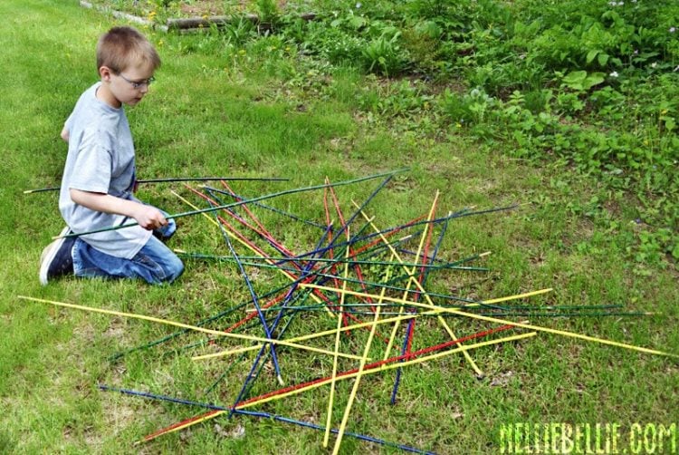 child playing colored pick up sticks game in lawn