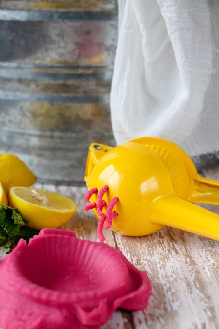 pink lemonade playdough being pushed through lemon squeezer