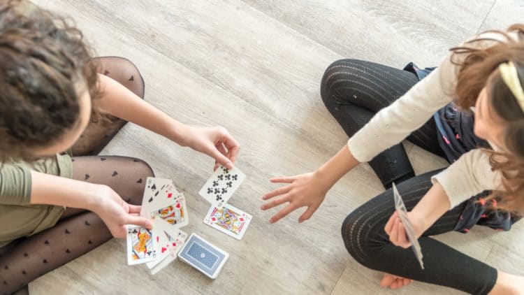 child playing card game with adult on the floor