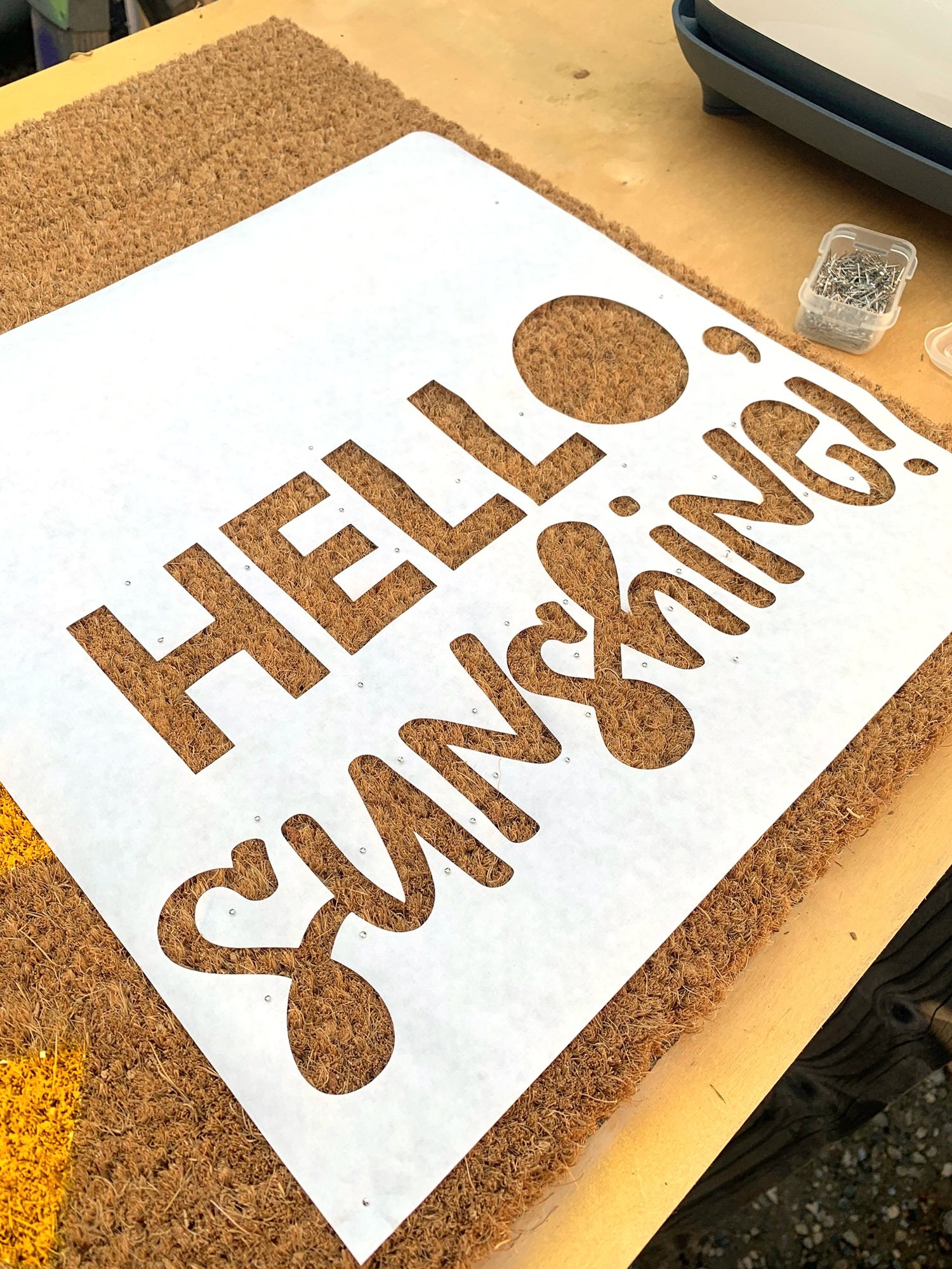 hello sunshine text stencil placed onto doormat