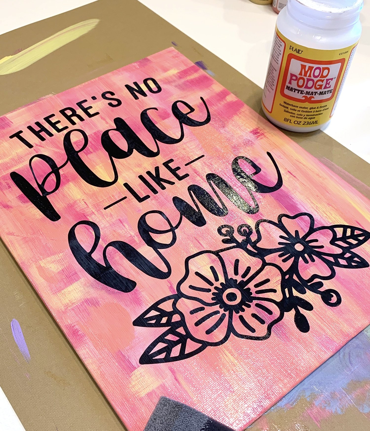 Applying Mod Podge to a hot mess canvas with vinyl quote