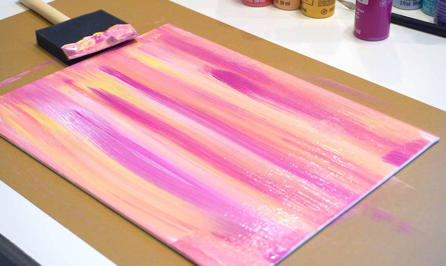 Pink, orange, yellow, and coral paint streaks on canvas with sponge brush