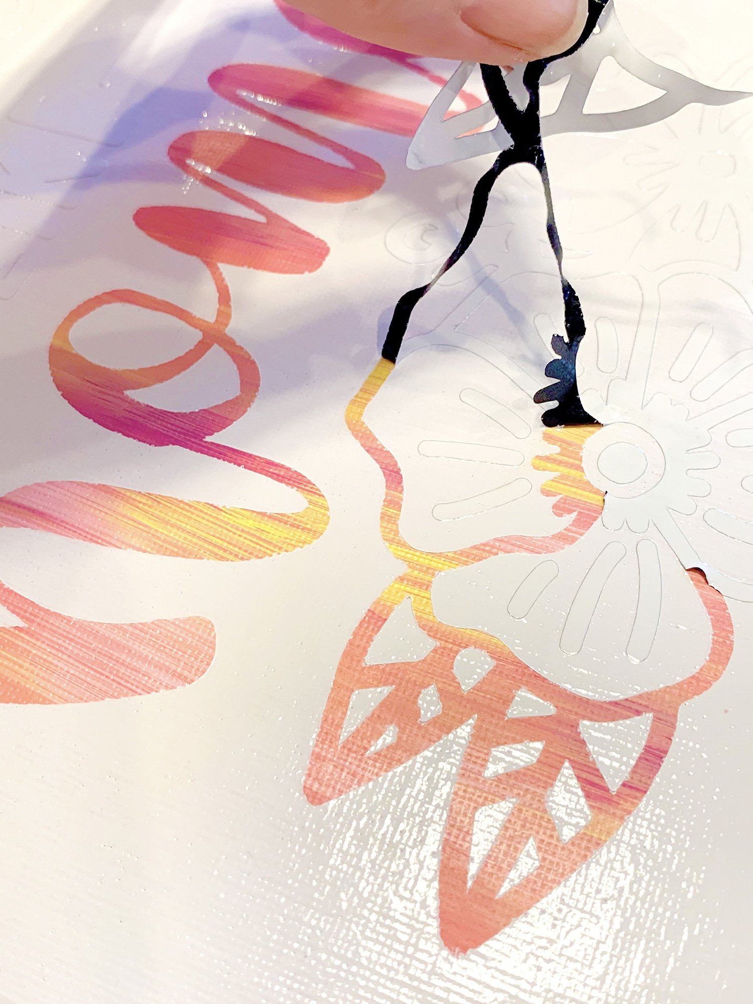 Peeling a reverse vinyl stencil from a hot mess canvas