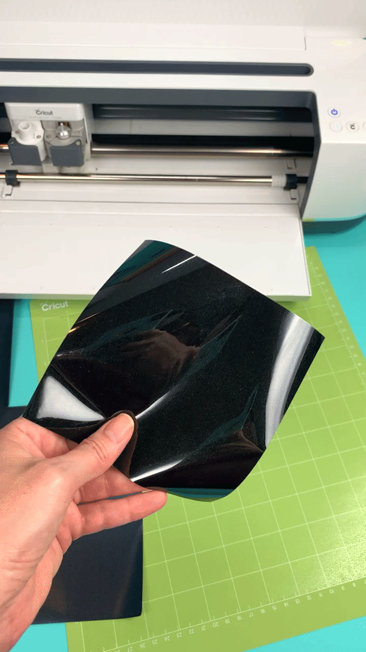 hand showing both sides on vinyl material in front of cricut machine