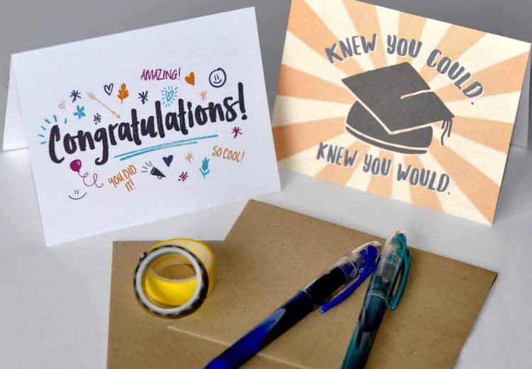two graduation cards with envelopes and pens