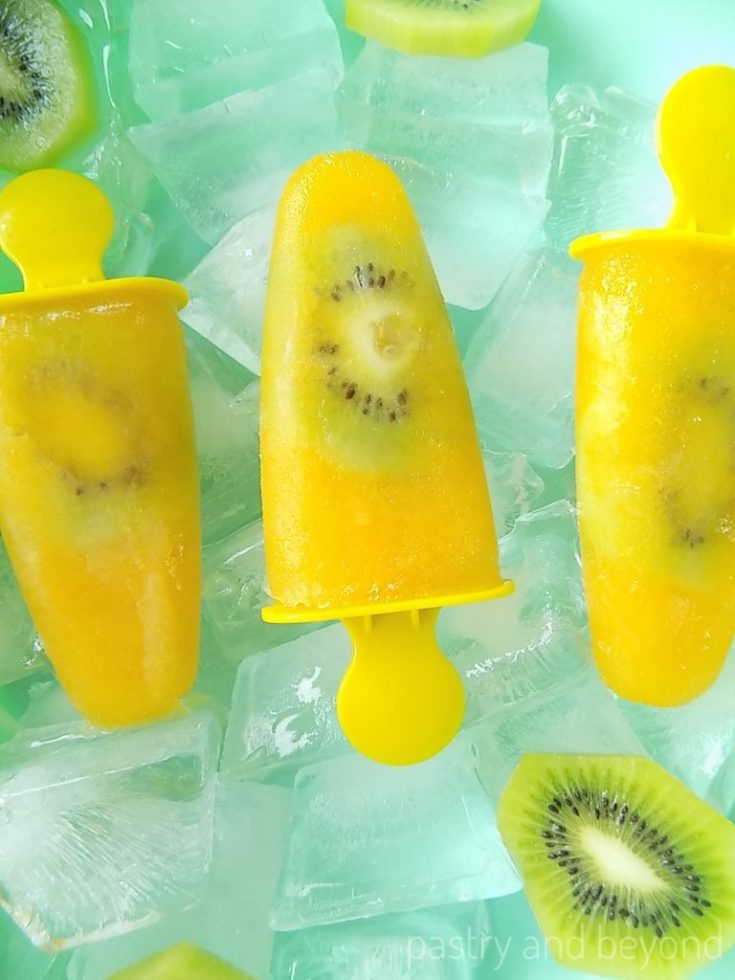 orange kiwi popsicles with sliced kiwi on ice