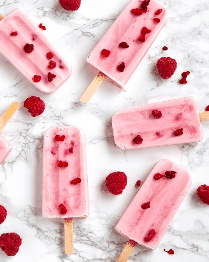 raspberry popsicles with raspberries sprinkled around