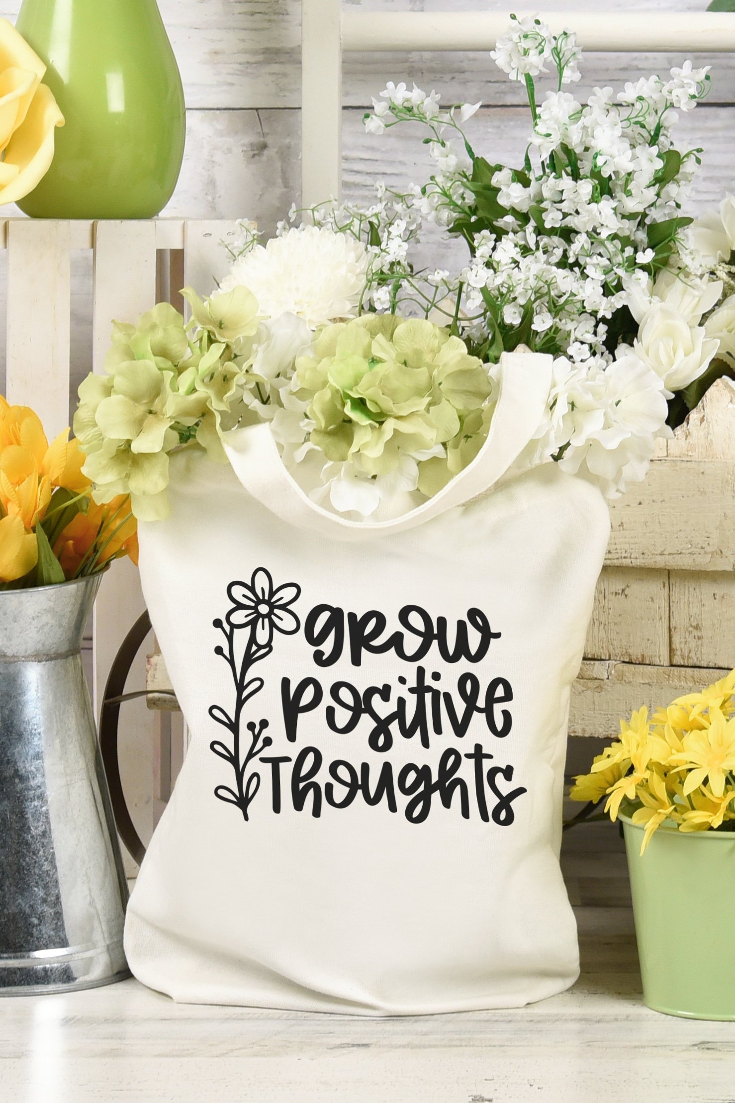 "Grow Positive Thoughts" Tote bag surrounded by white and yellow flowers