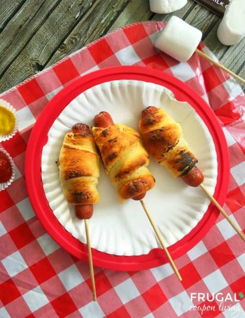 camping hot dogs on a stick on paper plate picnic table setting