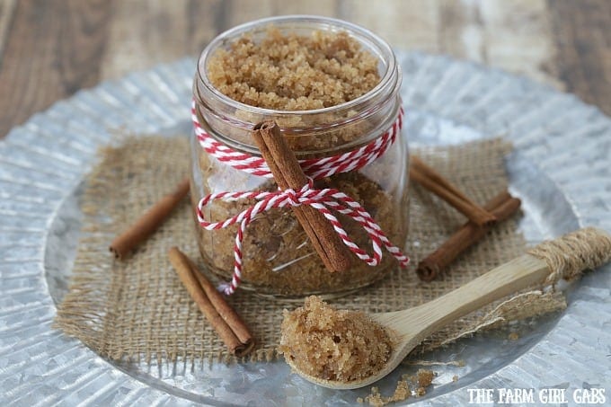 a jar of cinnamon sugar scrub with a small wooden spoon and cinnamon sticks