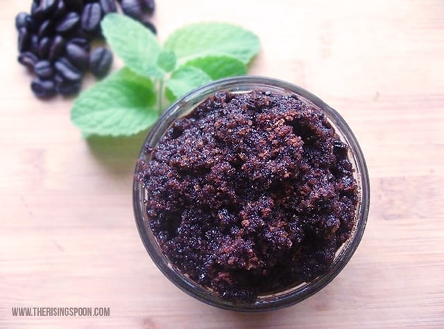 Close up of jar of brown coffee cacao and peppermint sugar scrub with mint leaves in background