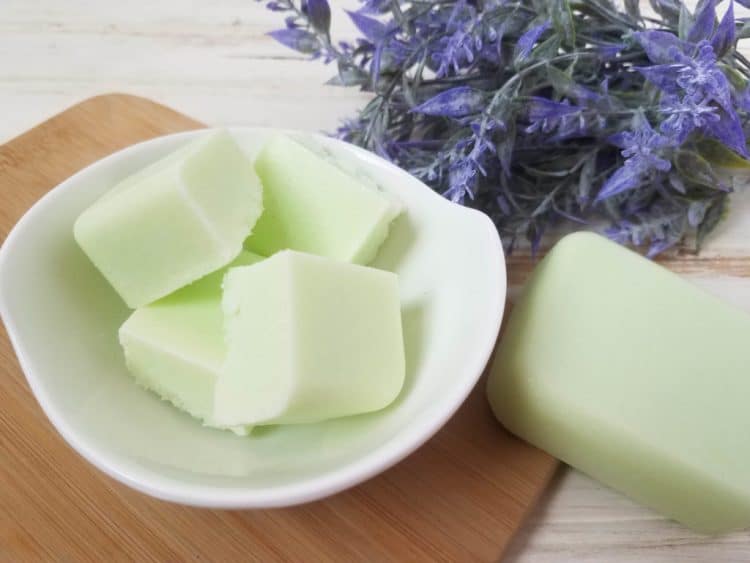 bowl of green cucumber melon sugar scrub bars on wood background with purple flowers