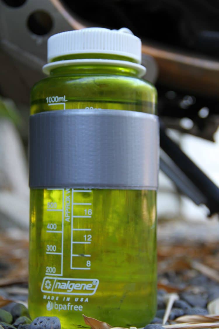 A close up of a transparent green bottle with duct tape on it.