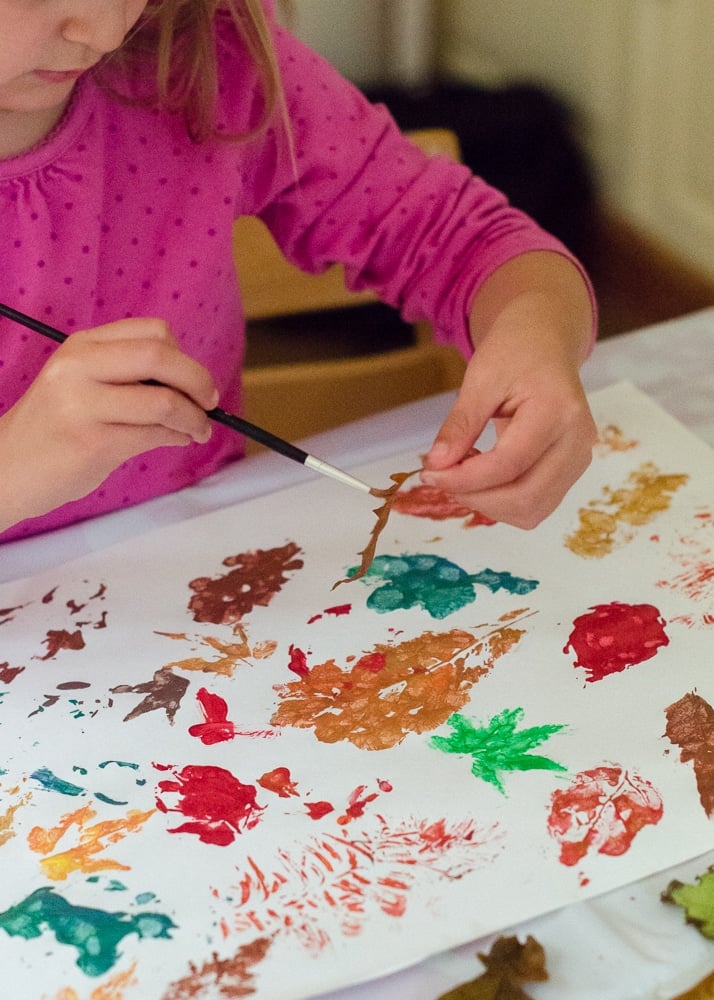 Child painting using leaves