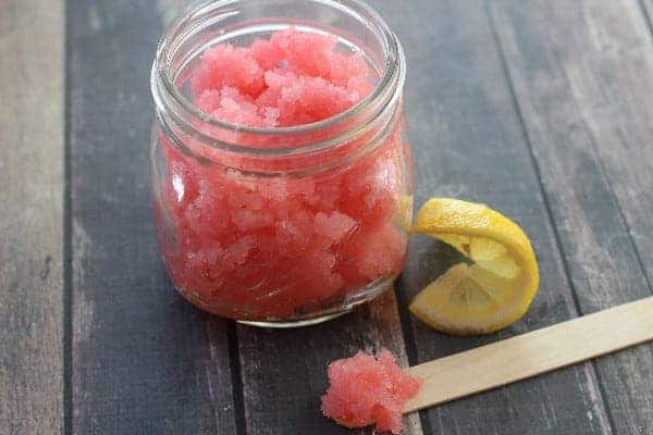 glass of pink lemonade sugar scrub with a lemon wedge